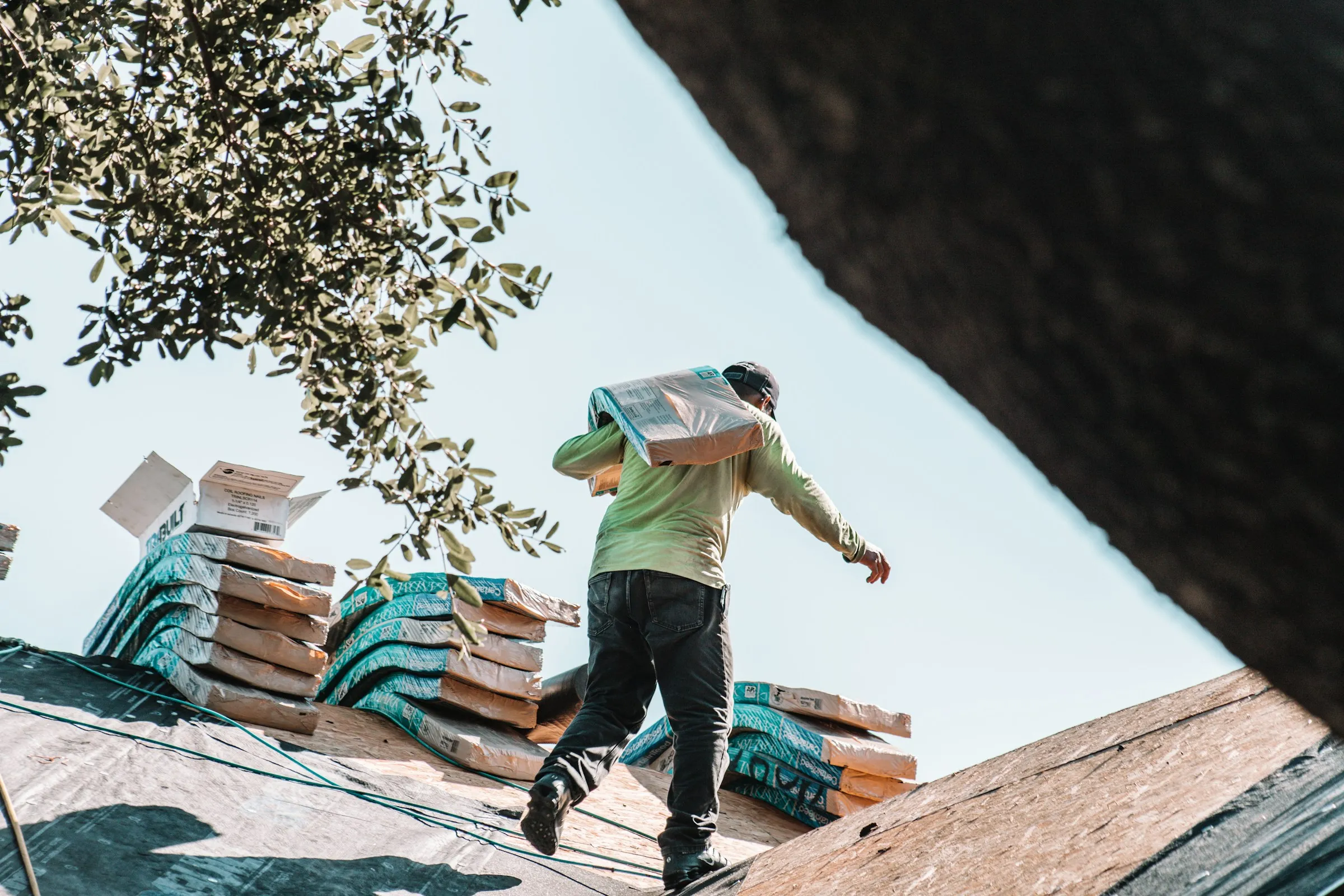 Man carrying shingles on roof.